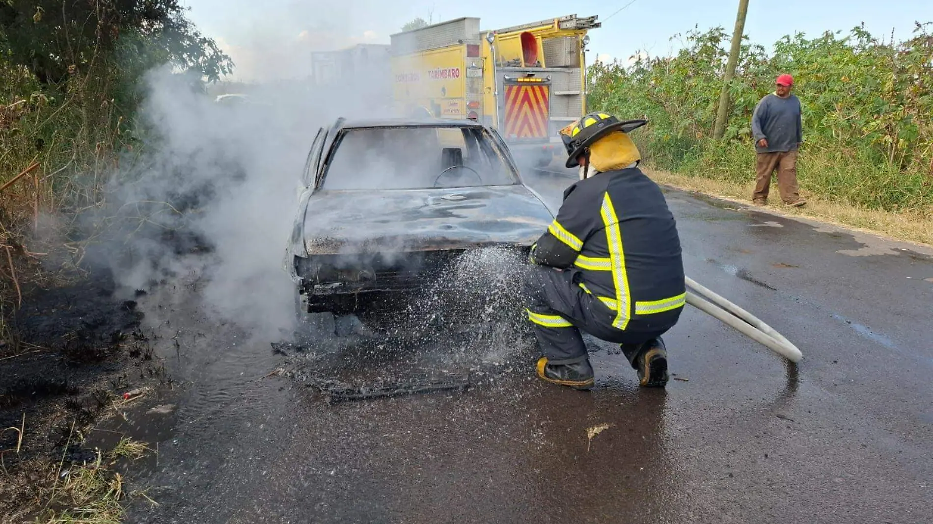 Bombero apagando vehículo incendiado en Tarímbaro